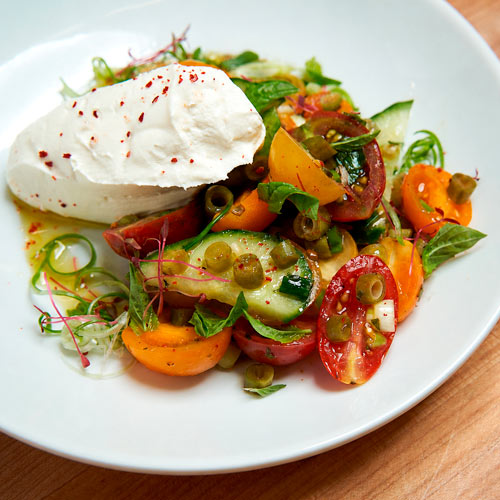 Plated seasonal salad with burrata and heirloom tomatoes