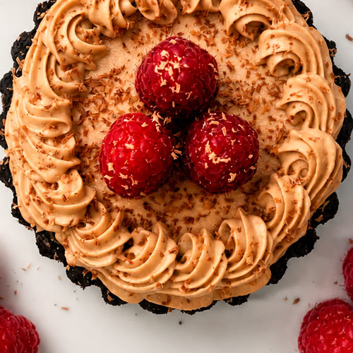 Celebration cake topped with piped frosting and raspberries