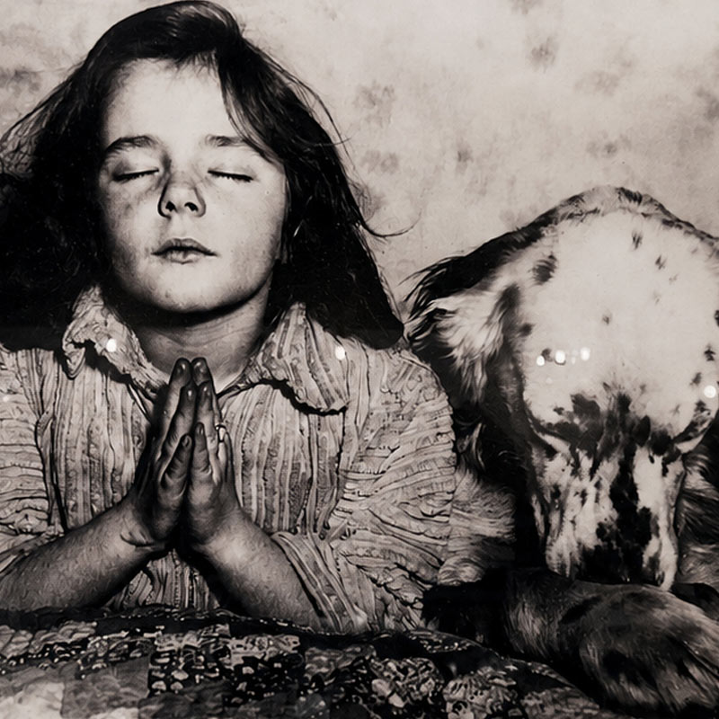Vintage photograph of a young girl praying beside her dog