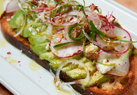 Avocado toast topped with sliced radish and greens